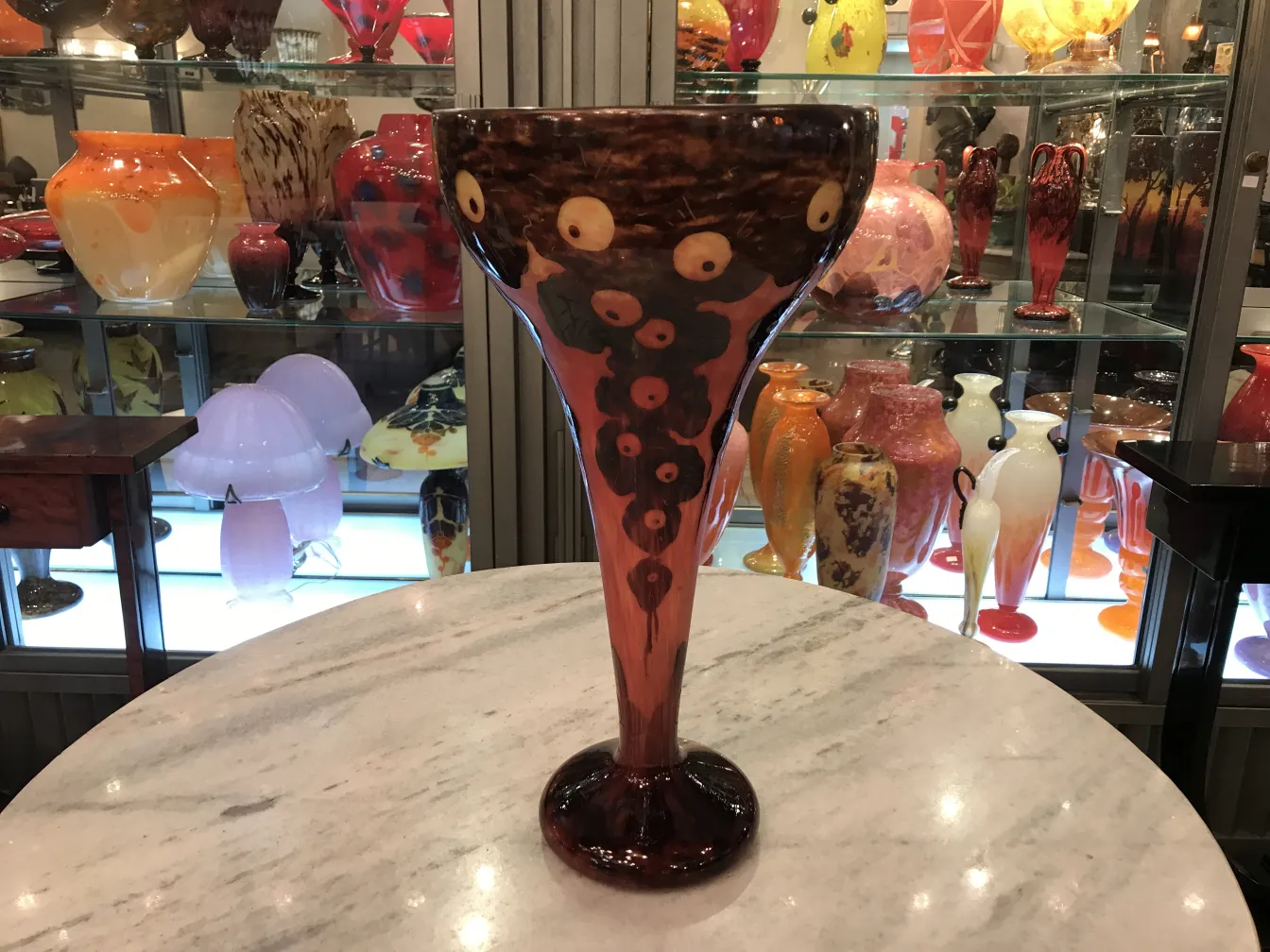 Vaso decorativo in vetro firmato Le Verre, circondato da oggetti d'antiquariato.