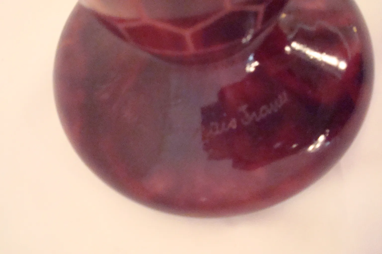 Antikes signiertes Glas mit dekorativem Muster in roten Tönen.