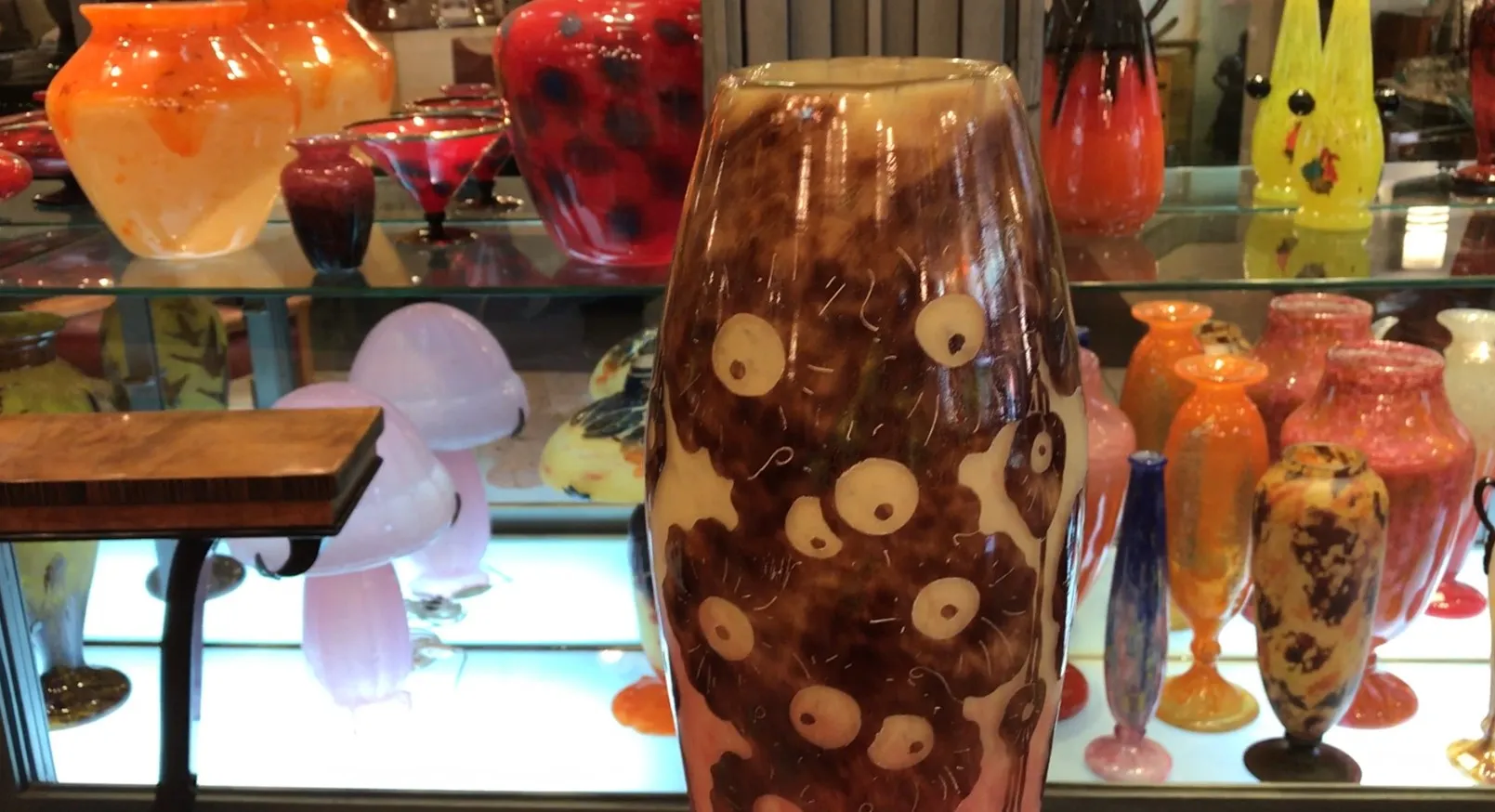 Vase decorativo de vidrio firmado Le Verre entre otros objetos coloridos.