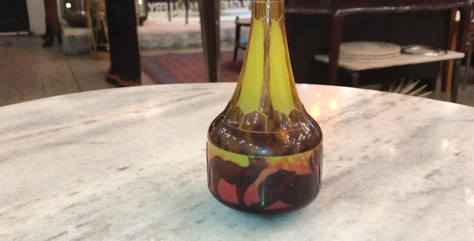 पुरातन हस्ताक्षरित ग्लास Le Verre जिसमें गर्म रंग और ऊंट की छायाएँ हैं।