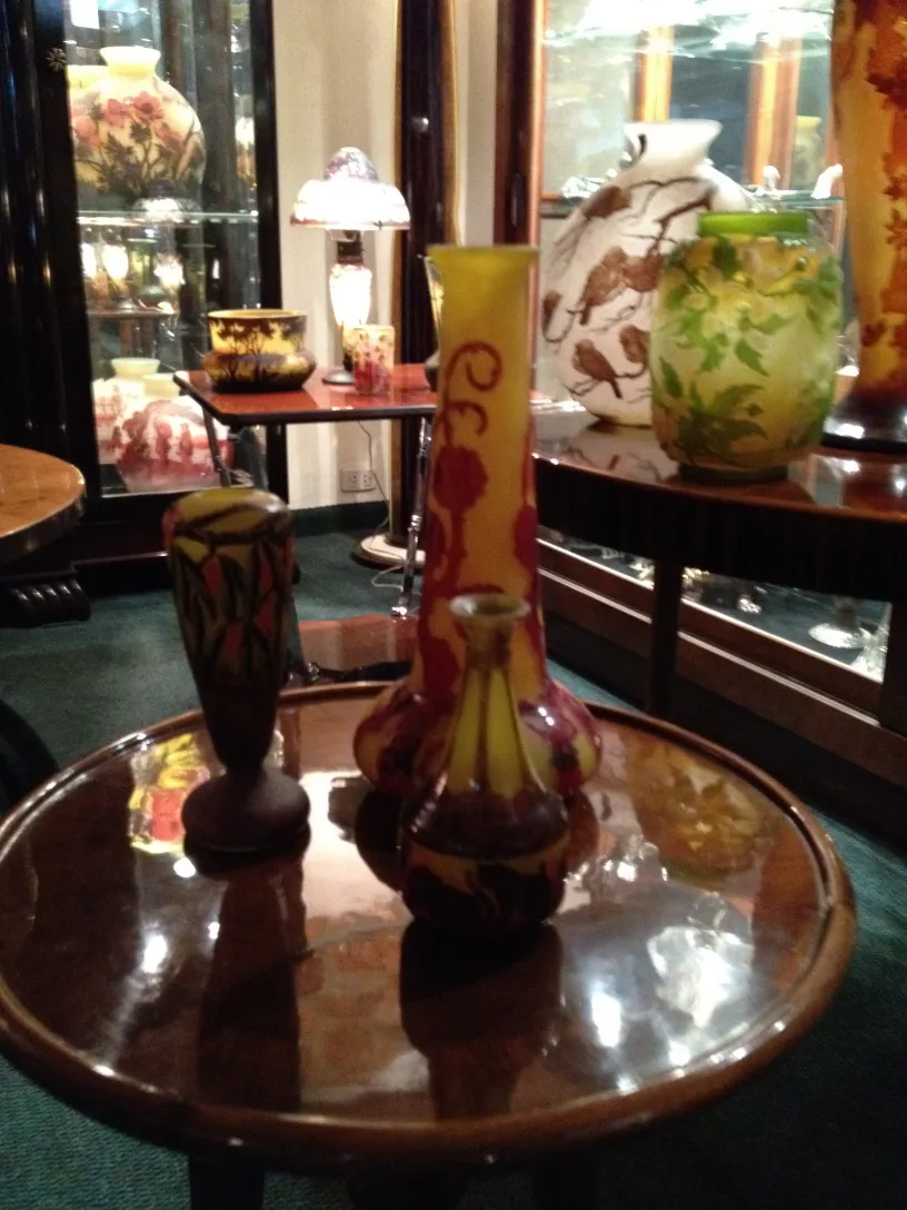 Signed glass Le Verre on an antique table, various vases in the background.
