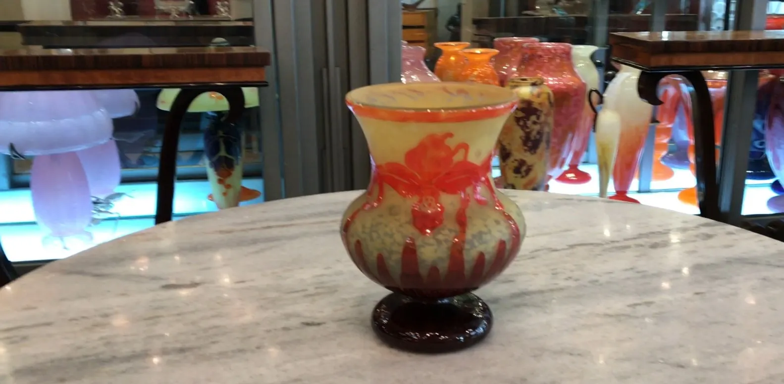 Antike Glasvase mit dekorativem Design in Orange und Gelb, das die Unterschrift hervorhebt.