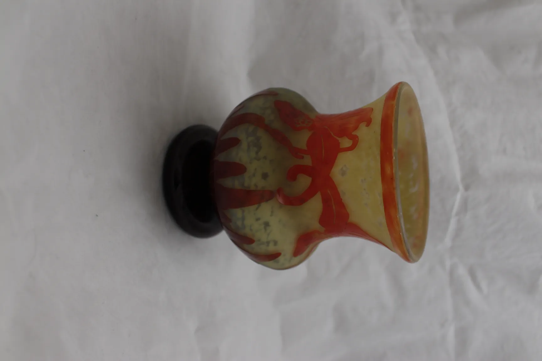 Antike Glasvase Le Verre mit rotem Design auf gelblichem Hintergrund.