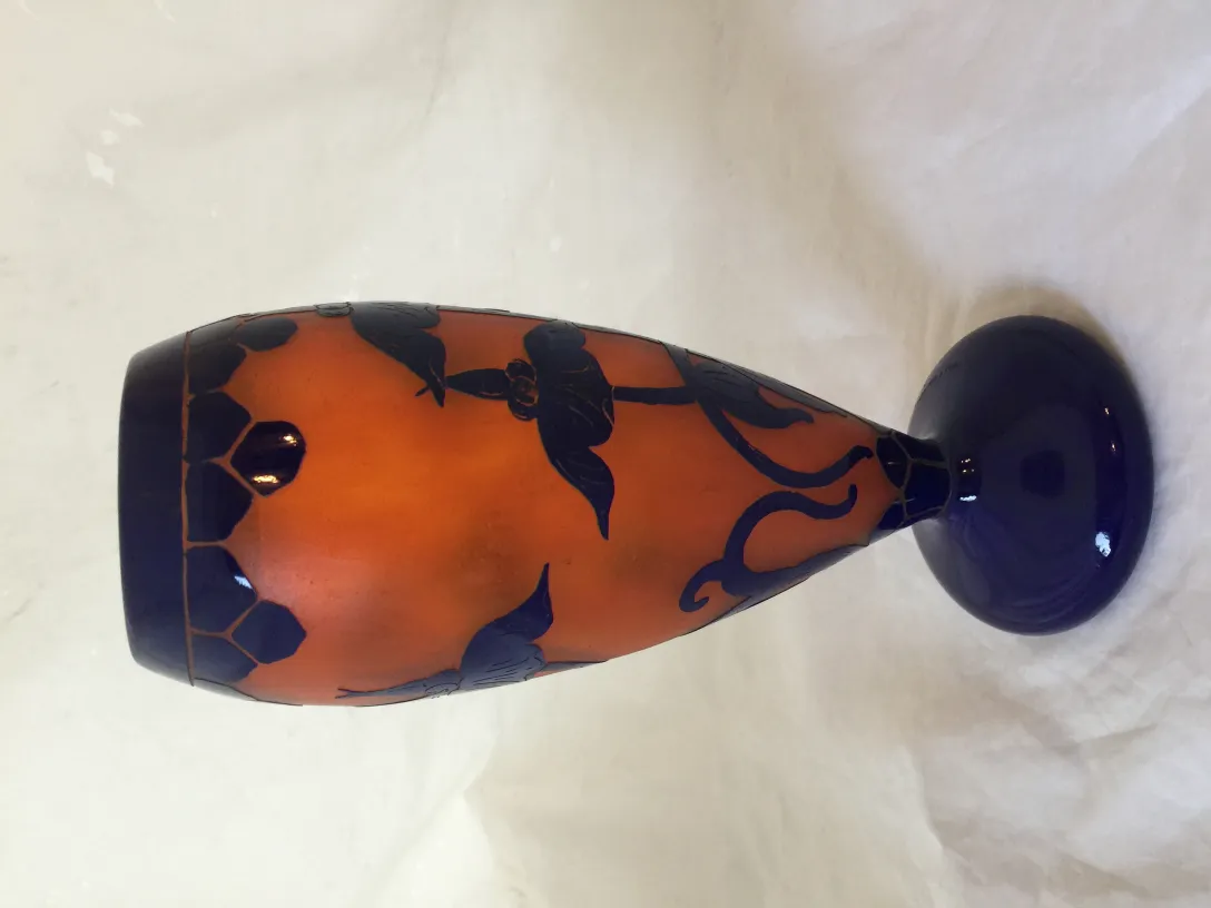 Signiertes Glas Le Verre mit dekorativen Motiven in Orange und Blau.