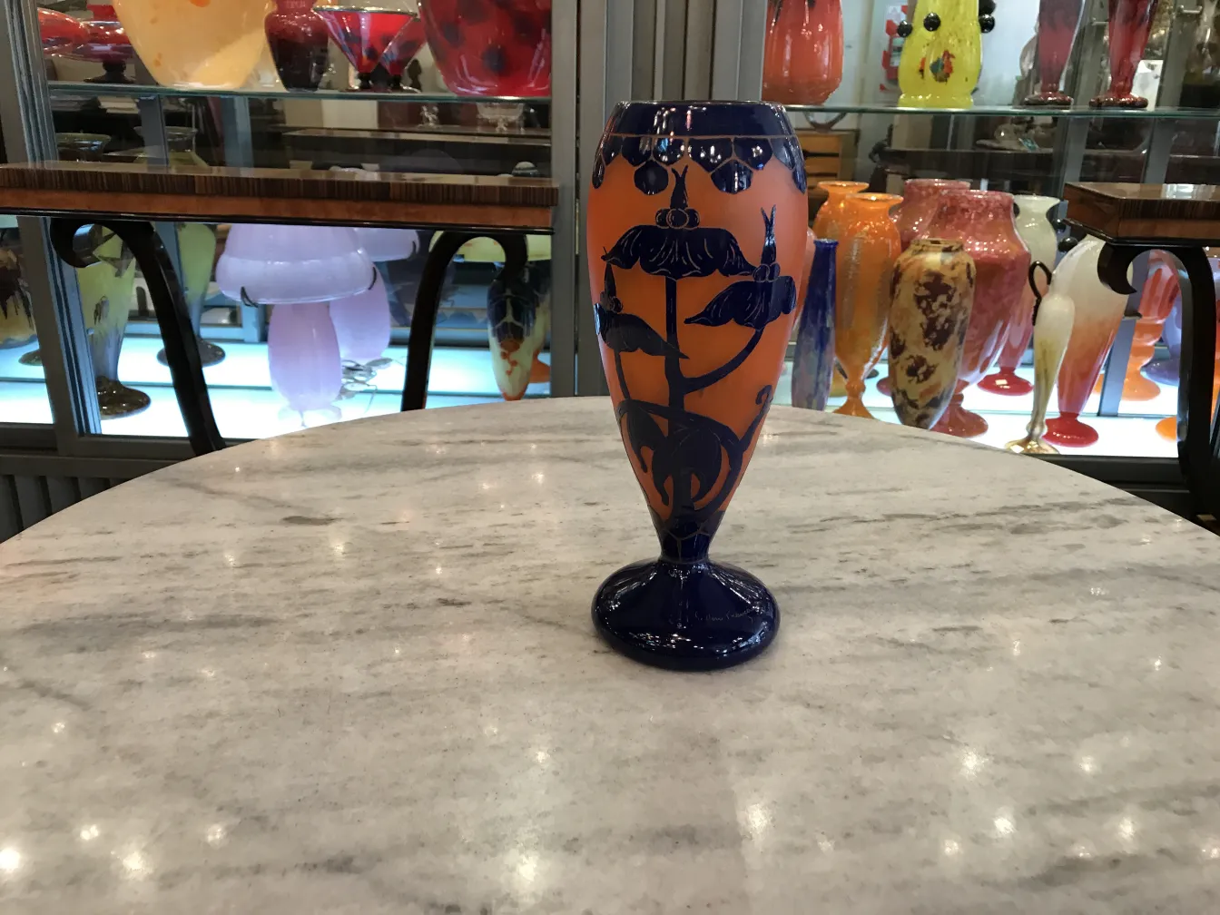 Antiguo vidrio firmado Le Verre con decoraciones florales en azul y naranja.