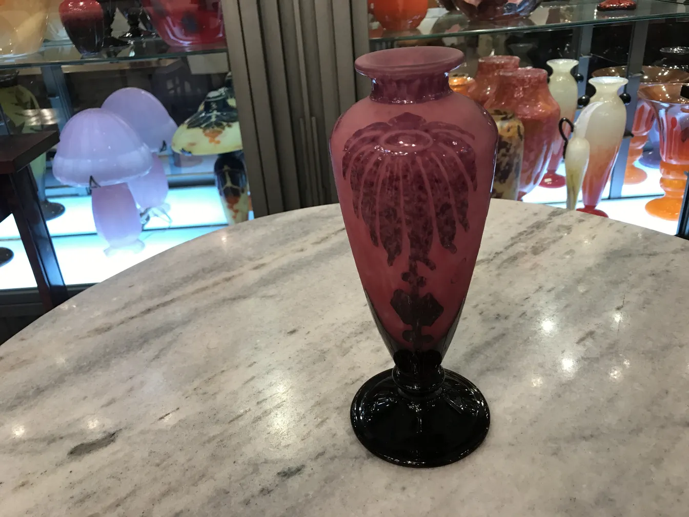 vase antico in vetro firmato, decorato in rosa e nero, esposto su uno sfondo di antiquariato.
