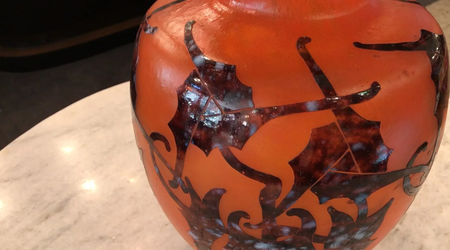 Антикварная стеклянная ваза с замысловатым дизайном, подписанная, выставленная в элегантной обстановке.