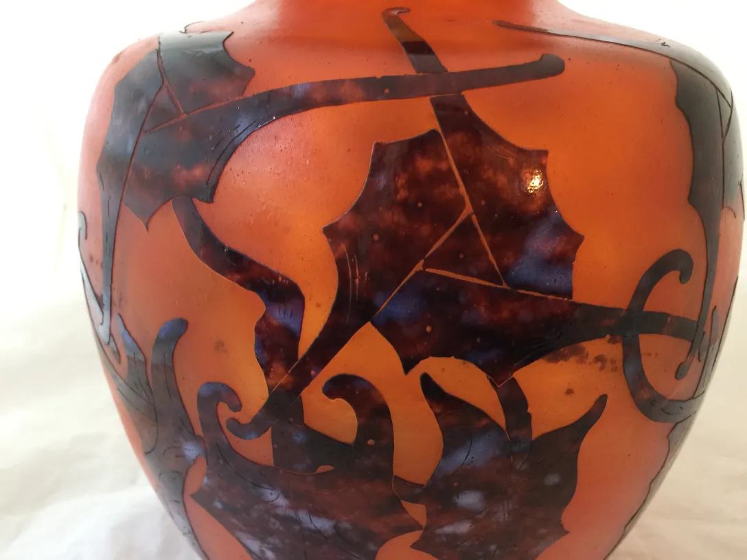 Vidrio firmado antiguo con diseño detallado de hojas.