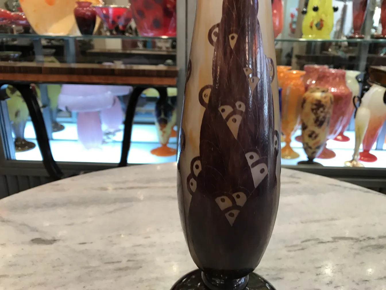 アンティークサイン入りグラス（Le Verre）、ユニークなデザインとスタイリッシュな形状で装飾され、カラフルなアンティークの背景の中にあります。