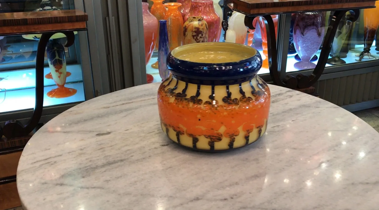 Vetro firmato Le Verre con design intricato arancione e giallo, circondato da antiquari.