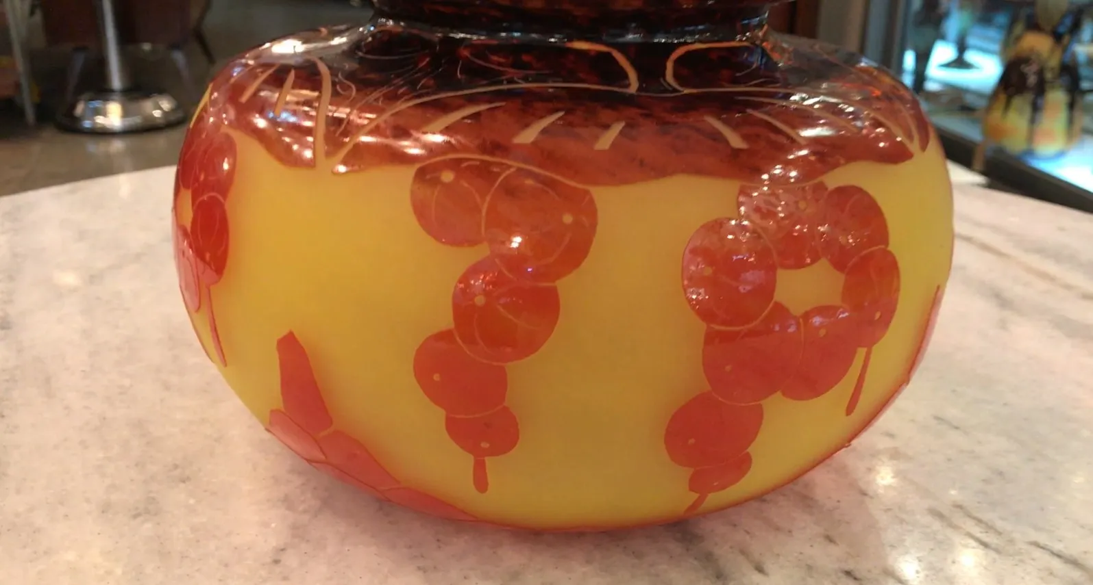 Vidro assinado Le Verre com decoração em amarelo e laranja, parte de um ambiente antigo.