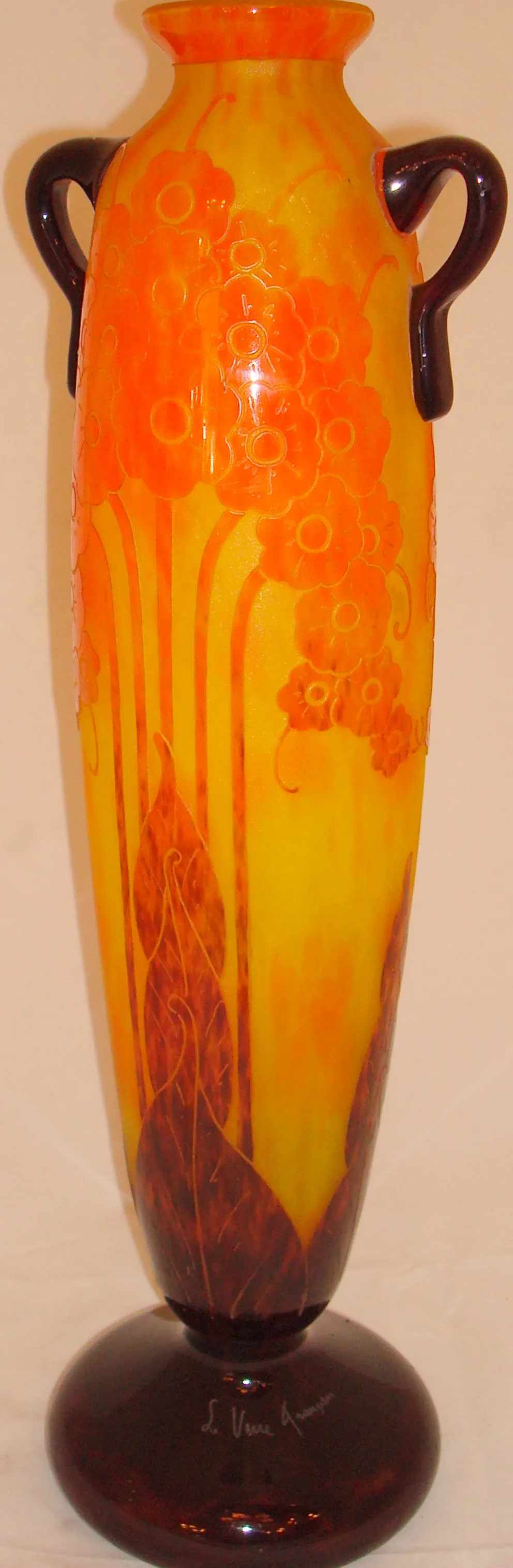 Antiguidades vidro assinado Le Verre com design floral em tons de laranja e amarelo, base escura.