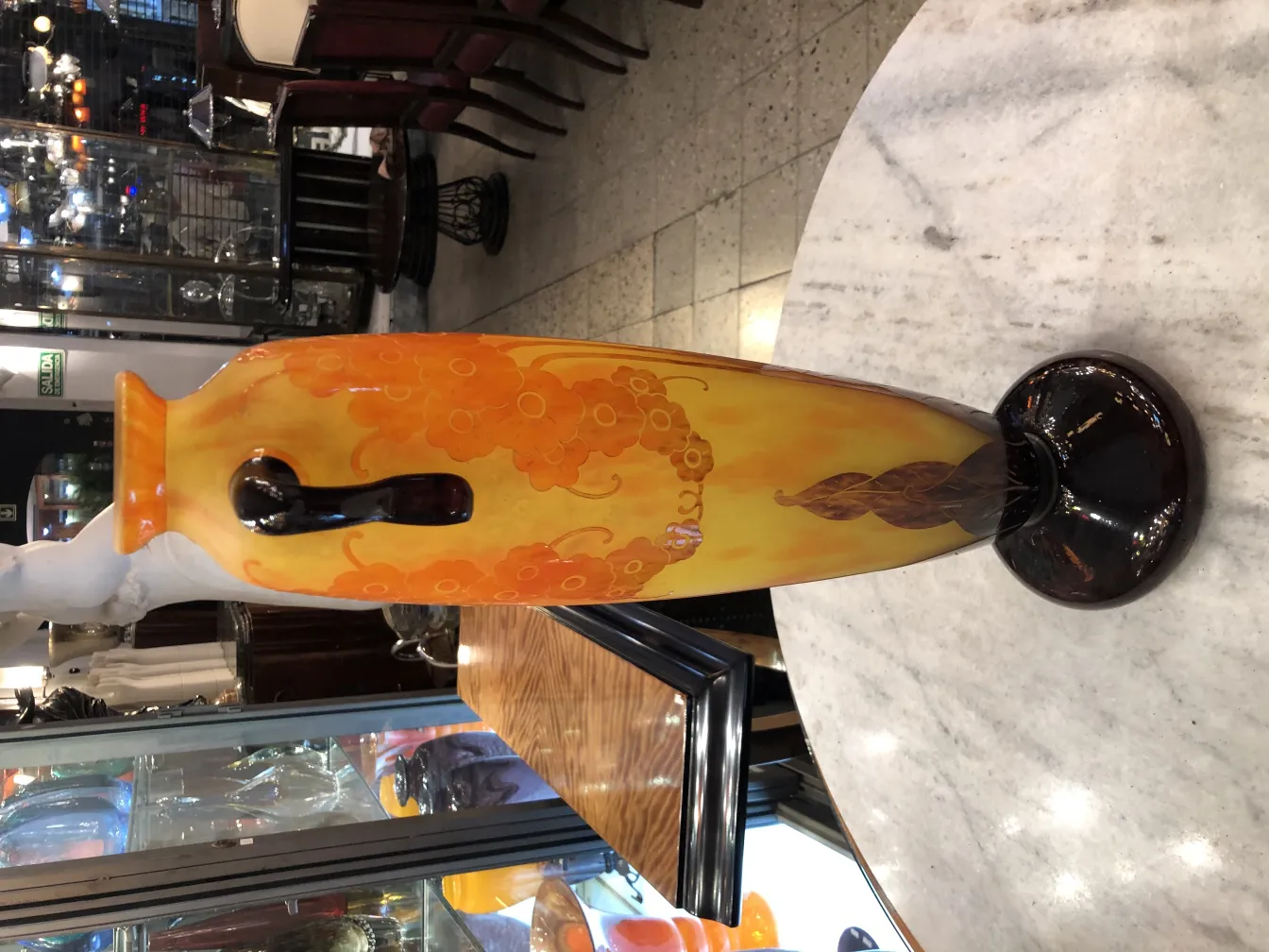 Vase en verre signé avec des tons d'orange et de jaune, décoré de fleurs, dans un cadre ancien.