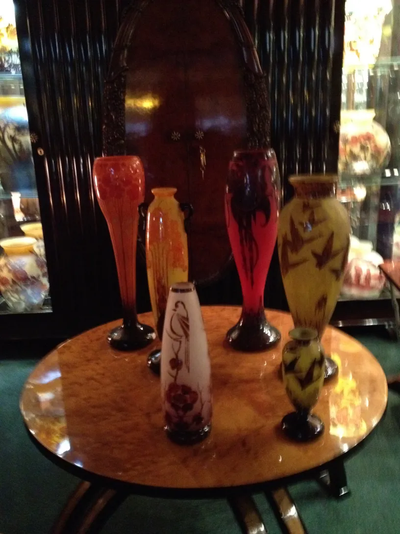 Six vases en verre antique sur une table, couleurs vives.