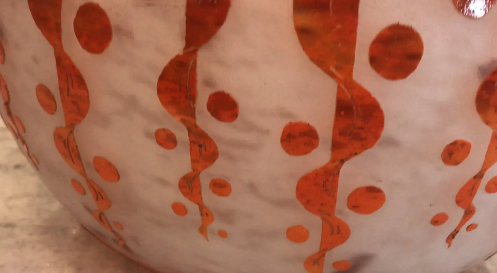 Antikes signiertes Glas mit orangen Details und runder Form.