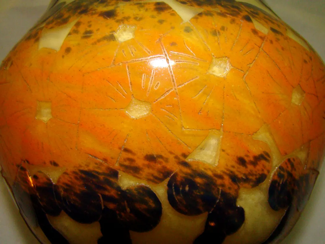 पुरातनता ग्लास पर हस्ताक्षरित जिसमें संतरी रंग के फूलों की सजावट है।