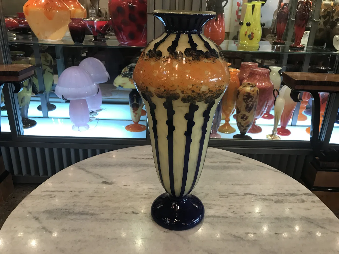 独特なカラフルな装飾が施された古いサイン入りグラス（Le Verre）が他のアンティークの中に展示されています。