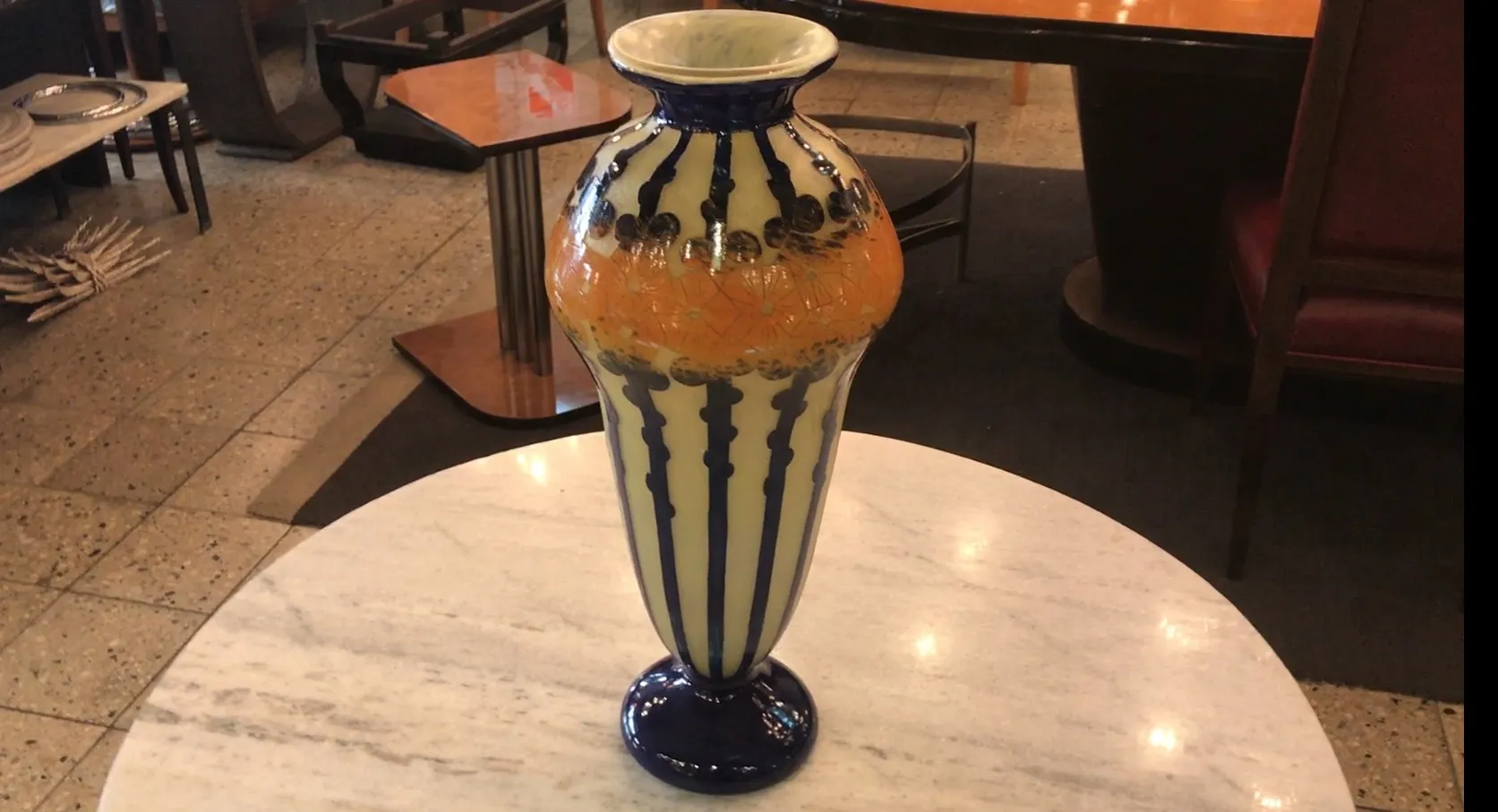 Antike Vase aus signiertem Glas Le Verre, dekoriert mit lebhaften Farben auf hellem Hintergrund, auf einem Tisch.