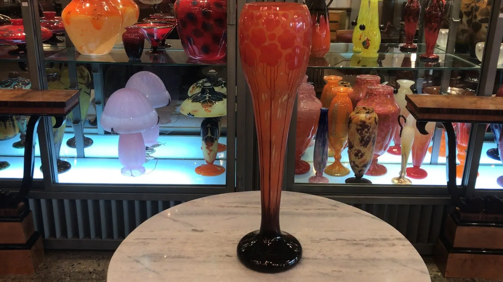 vase en verre signé le verre sur un comptoir noir avec d'autres antiquités derrière