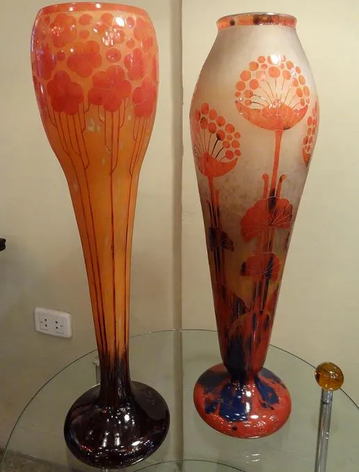 Deux vases en verre signé avec une décoration florale dans des tons chauds.