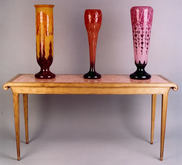 Trois vases en verre antiques, couleurs et formes variées, fond neutre.