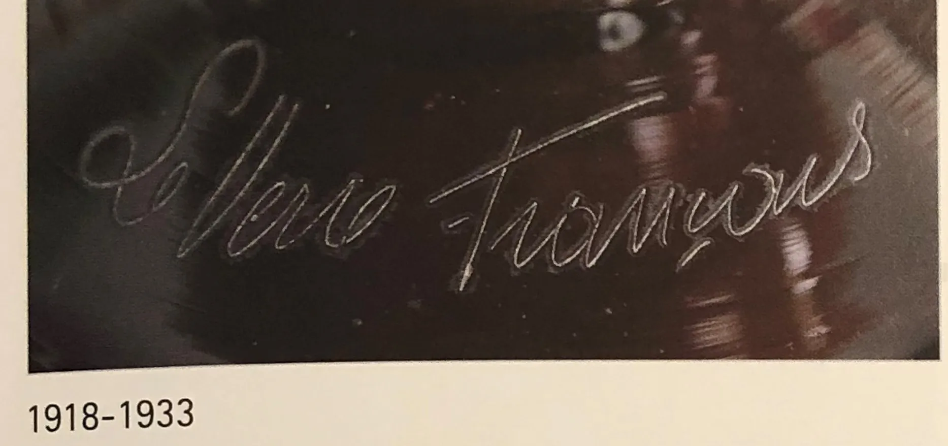 Vidrio antiguo firmado con un diseño fluido, fondo oscuro