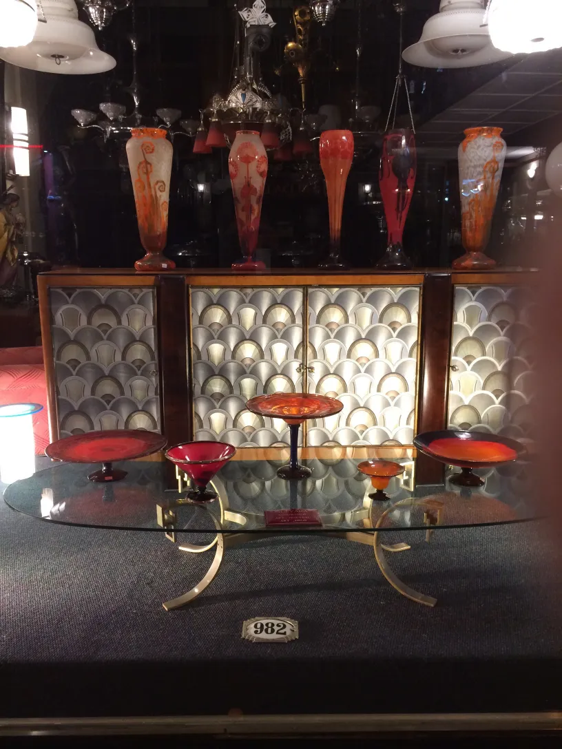 Vidrio firmado Le Verre expuesto en un ambiente antiguo, con decoraciones en tonos vibrantes.