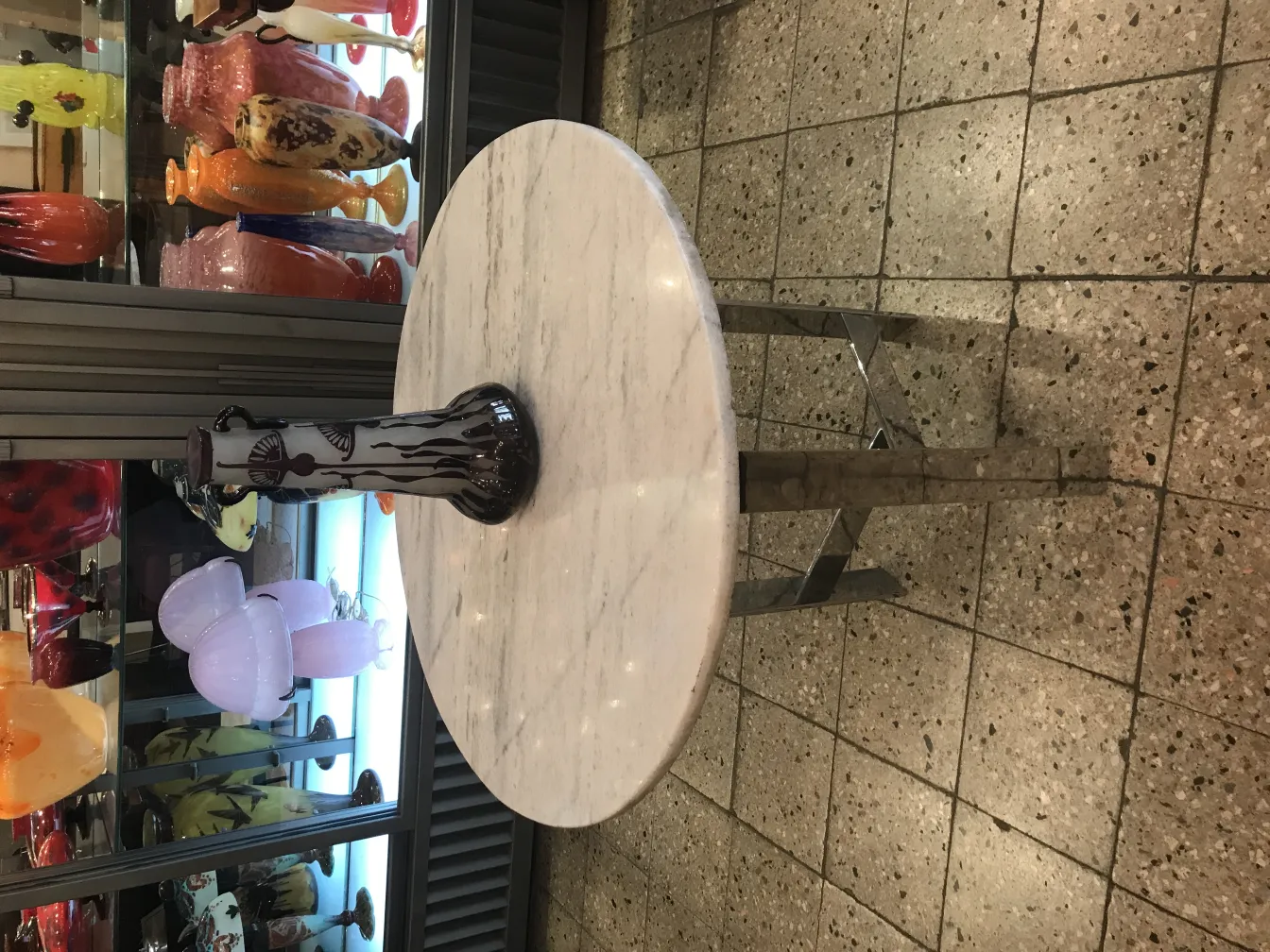 Vidro assinado Le Verre com decoração artística ao fundo.