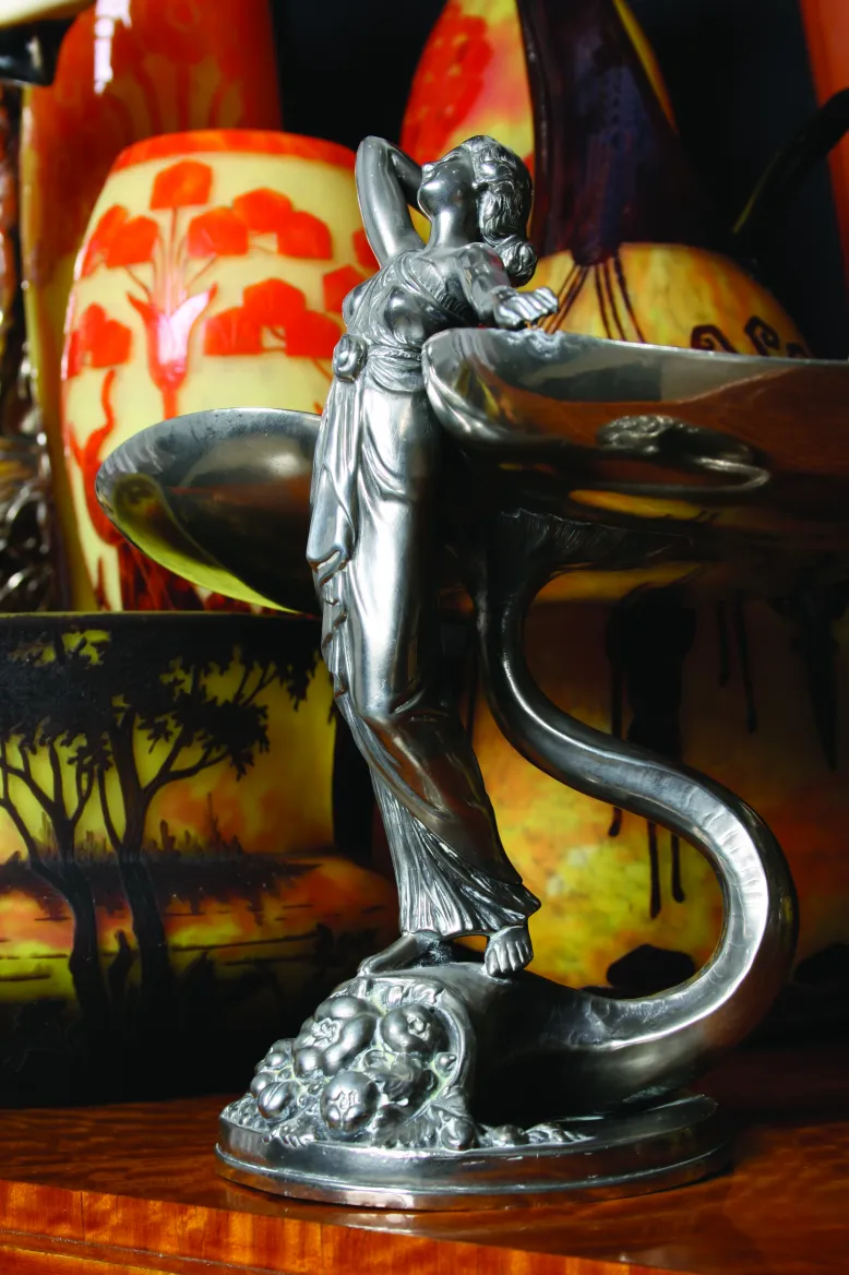 escultura en metal de figura femenina, decoraciones de vidrio al fondo