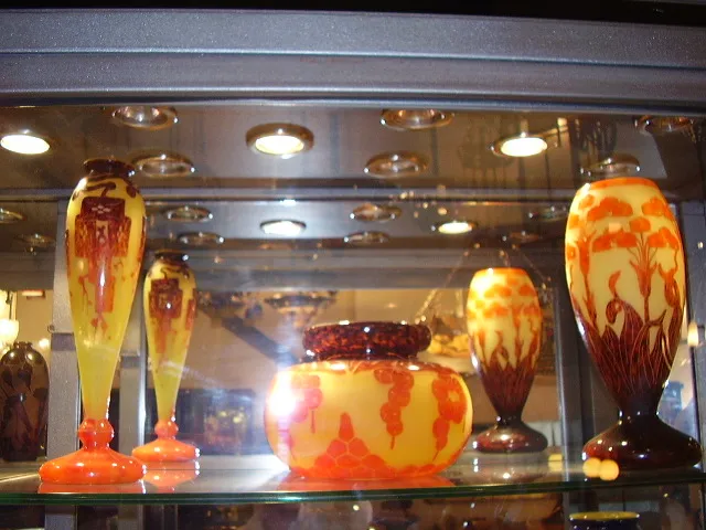 Antikes signiertes Glas Le Verre mit bunten Motiven in einer Vitrine.