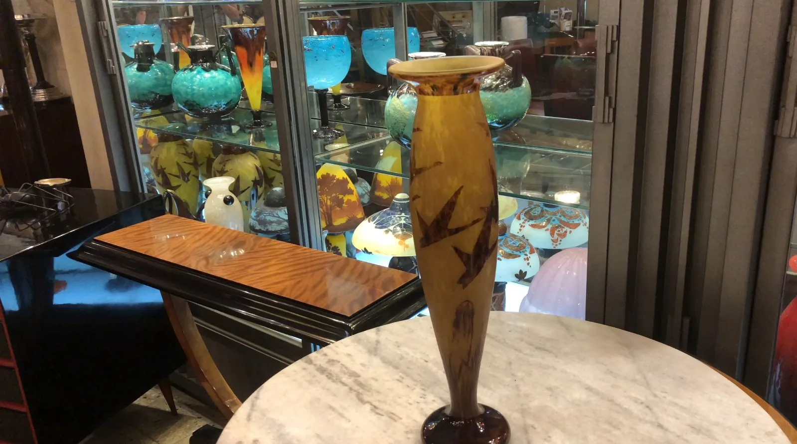 زجاج موقّع قديم Le Verre مع أشكال وتصميمات فنية. الخلفية تحتوي على قطع أثرية ملونة.