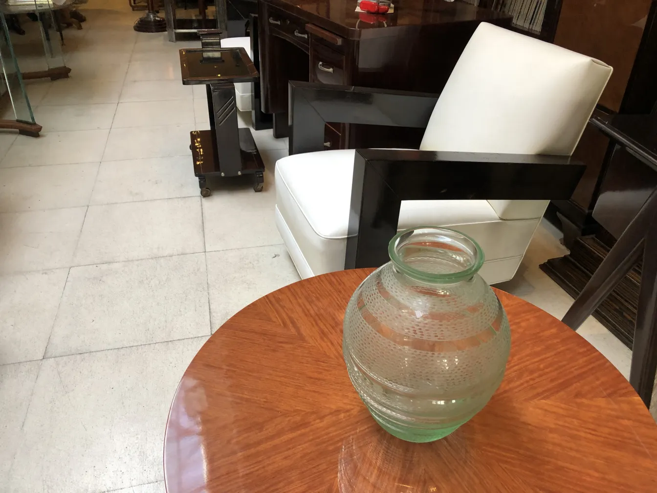 Vaso de vidro assinado Daum Nancy sobre mesa de madeira em um ambiente antigo.