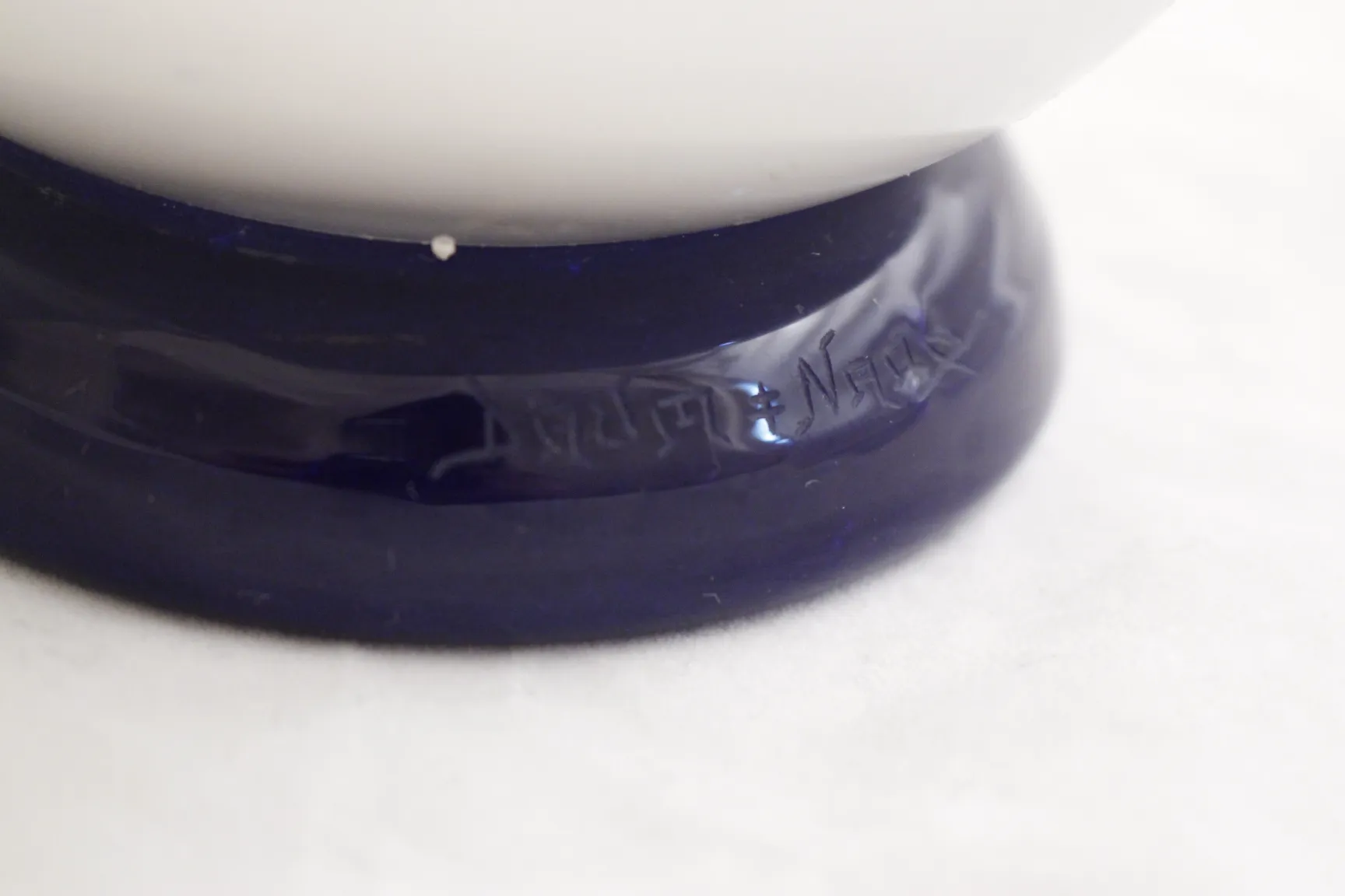 Detalle de una antigua pieza de vidrio firmado Daum Nancy con un fondo claro.