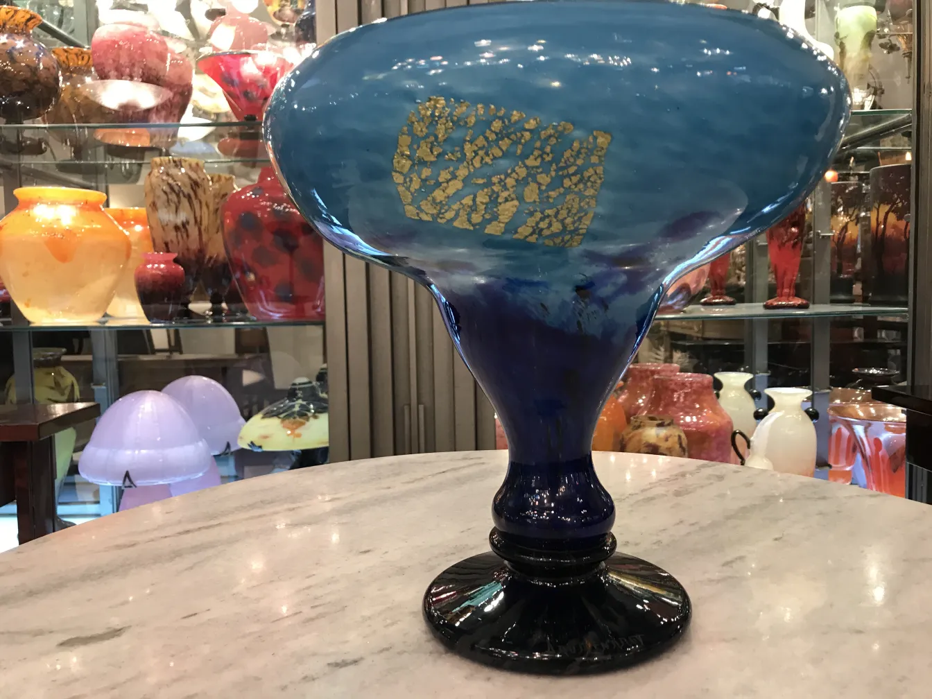 vue latérale d'une ancienne pièce de verre signé daum nancy, arrière-plan coloré avec d'autres objets