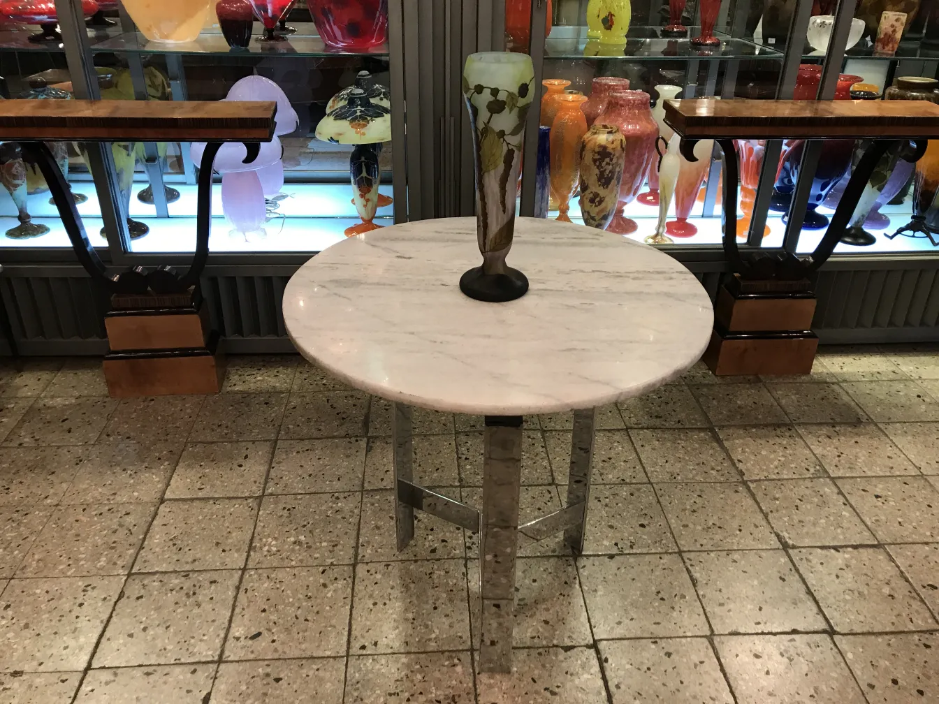 Vaso de vidro assinado Daum Nancy em exibição com outras antiguidades coloridas