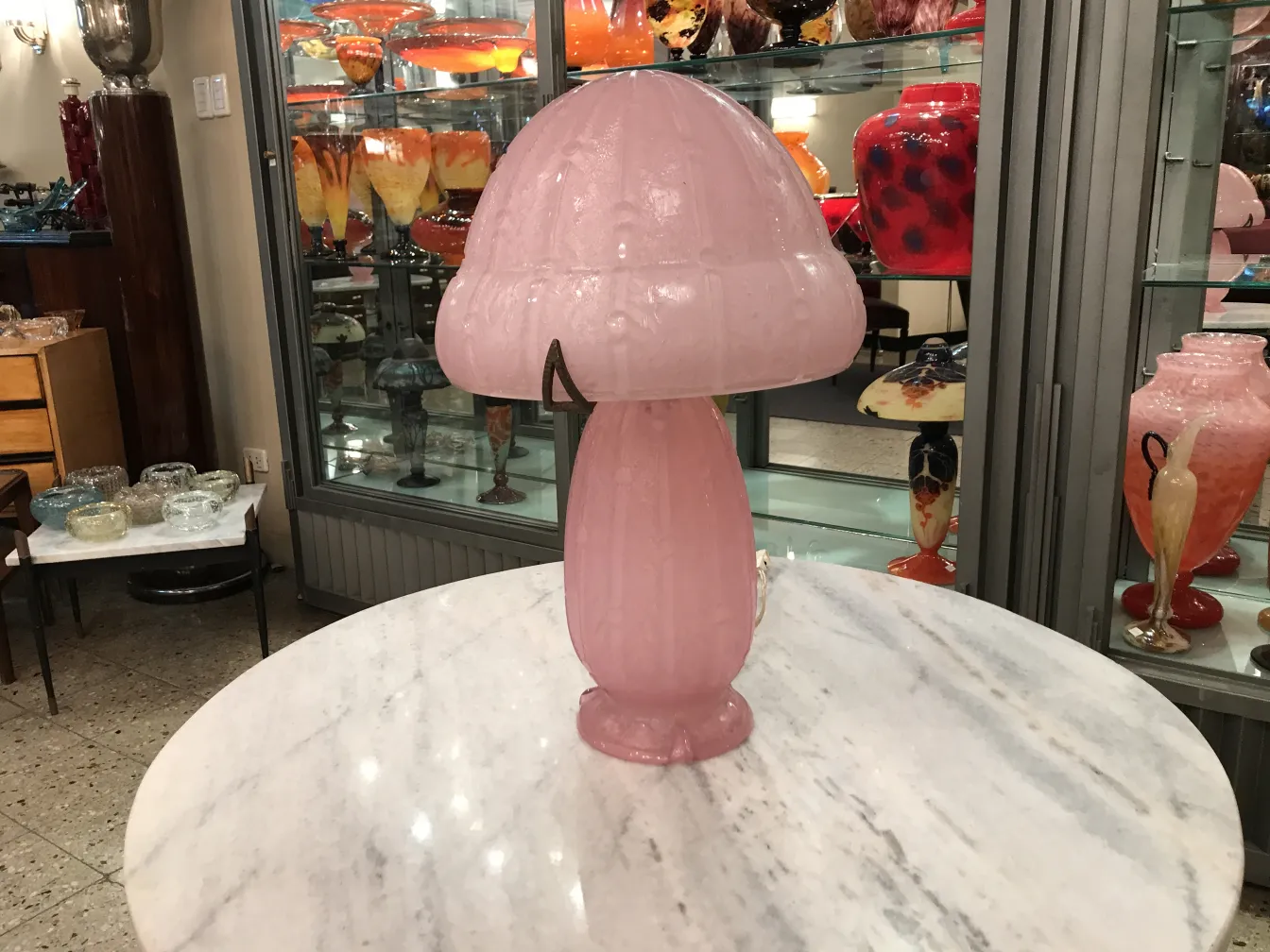 Lâmpada rosa de vidro assinado Daum Nancy em um ambiente de antiguidades.