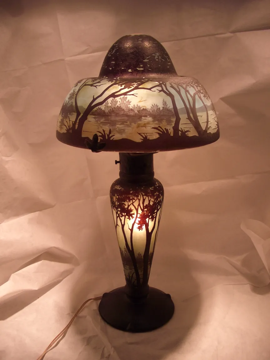 Ancienne lampe avec verre signé Daum Nancy, illuminée, avec détails de paysages.