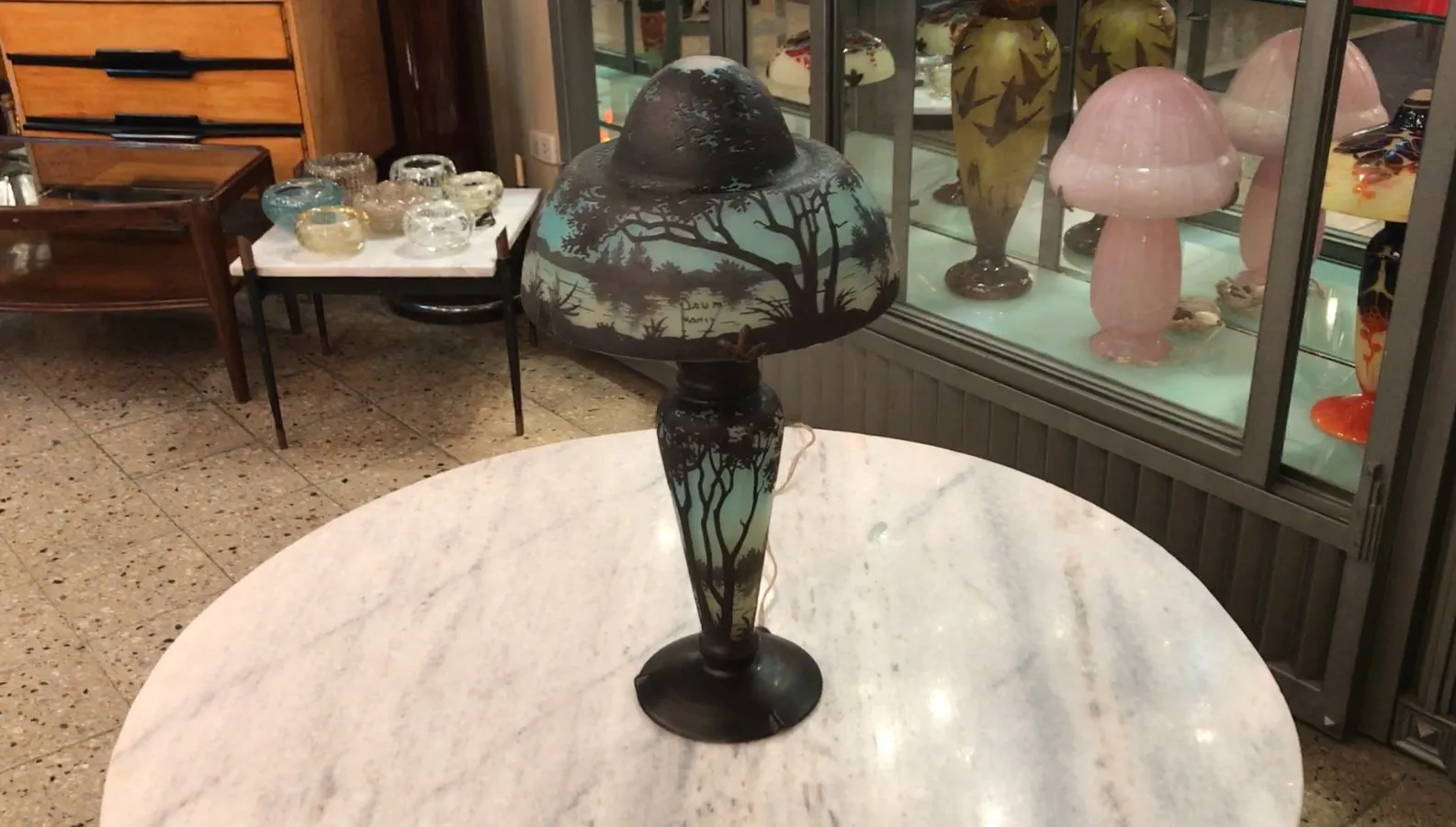 lampada antica con vetro decorato, firmata daum nancy, circondata da oggetti vintage