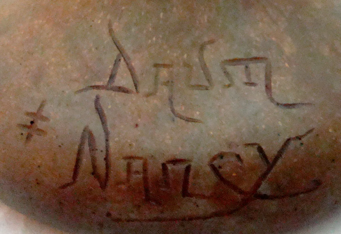 زجاج قديم مع توقيع مرئي لداوم نانسي في سياق الع antiques.