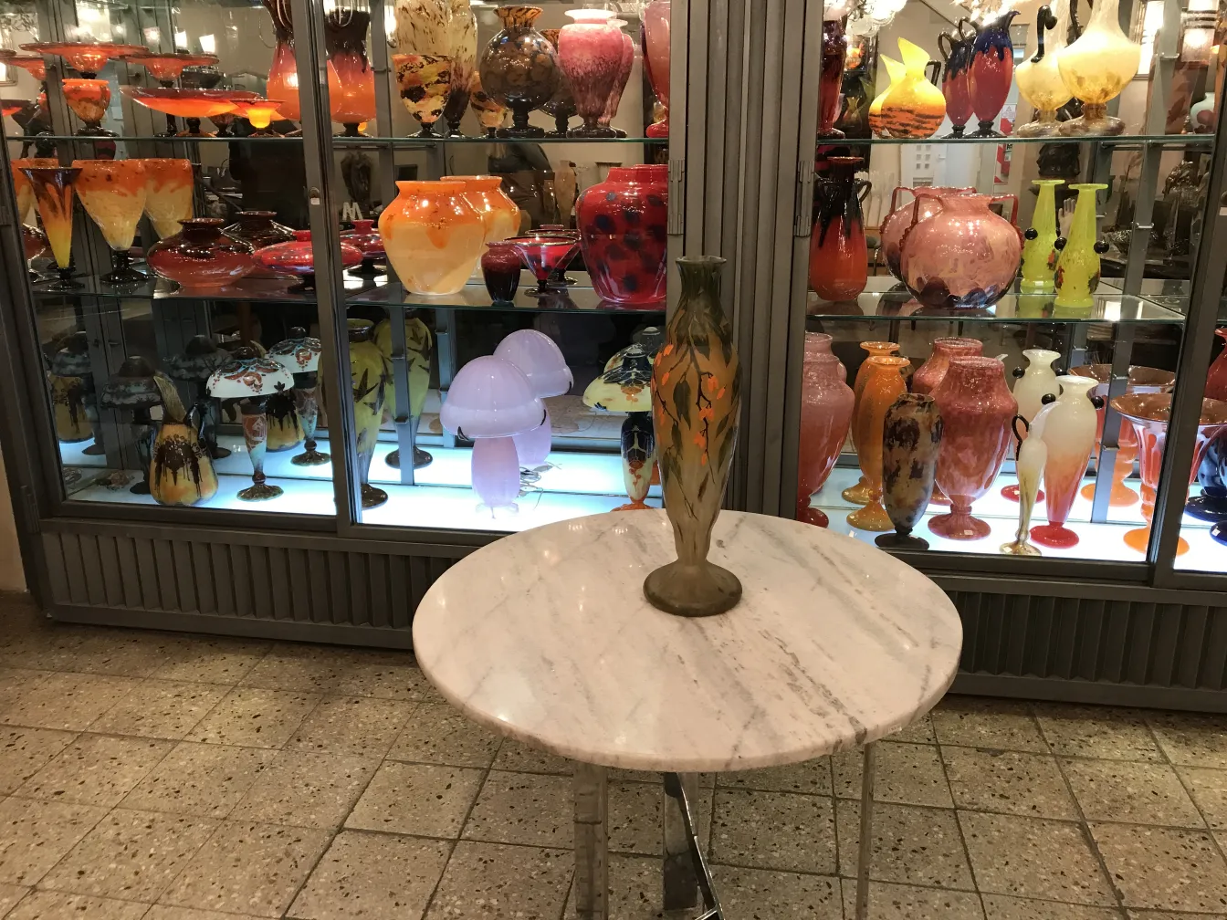 Signierte Glasvase von Daum Nancy in einer Vitrine mit verschiedenen dekorativen Gegenständen.