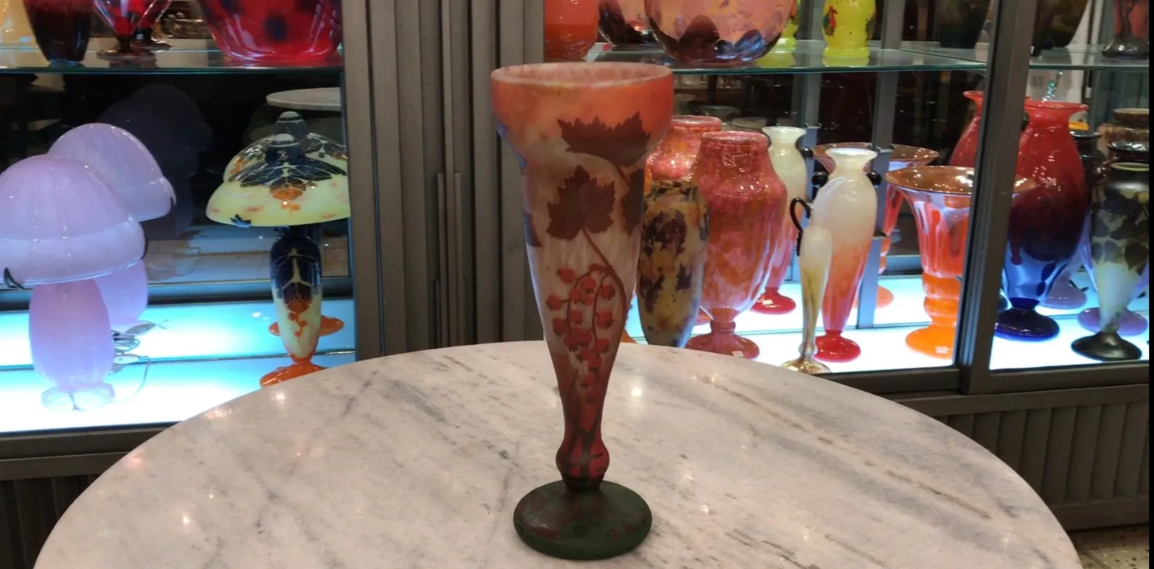 古董达姆南希花瓶，带有叶子和葡萄的设计，展示在其他古董之间。