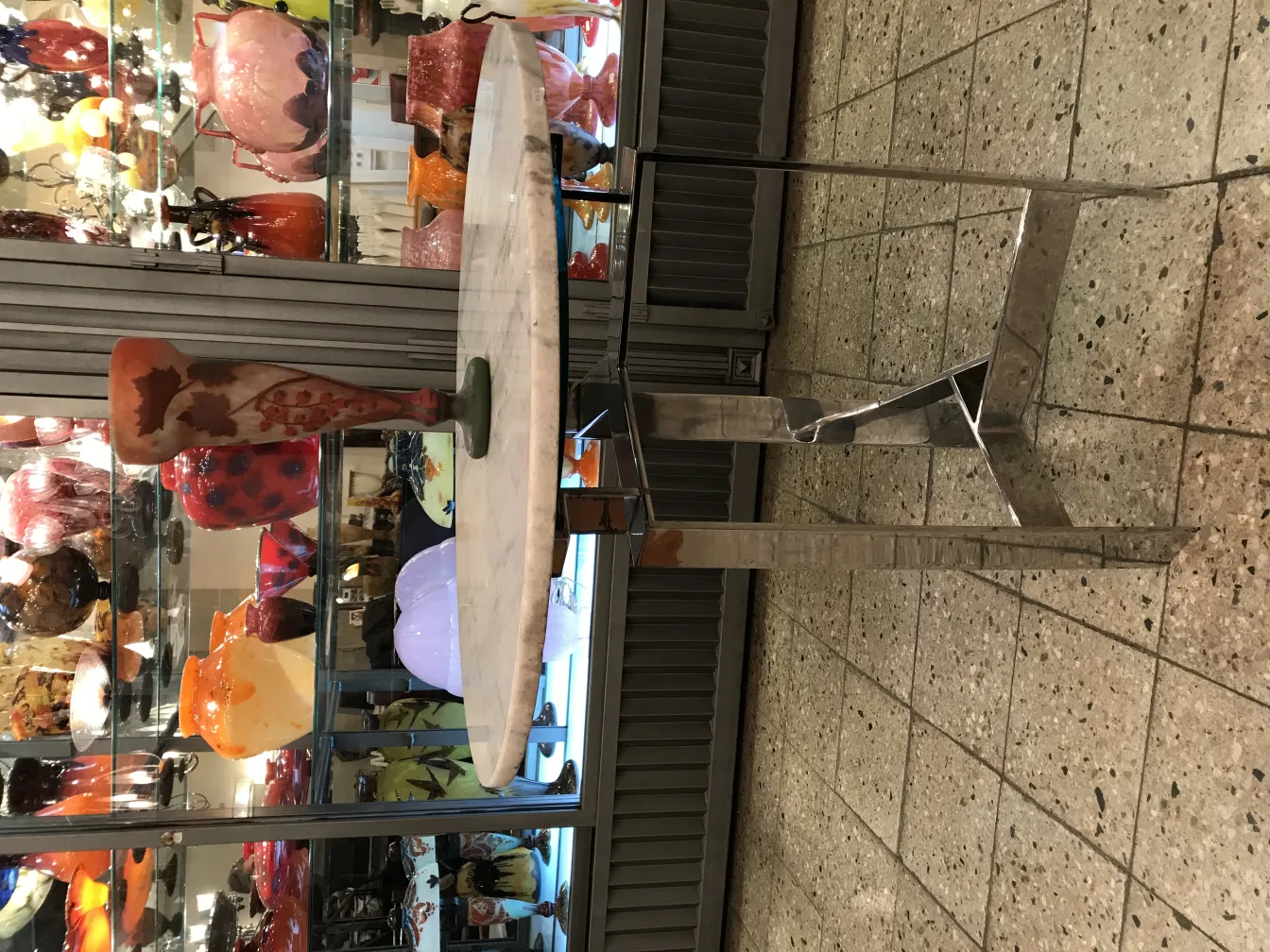 サイン入りグラスDaum Nancy、緑色のベースにカラフルなデザインが施され、他のガラス製品とともに展示されています。