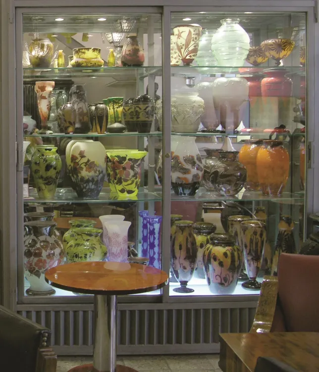 Display of antiques with signed glass Daum Nancy on shelf