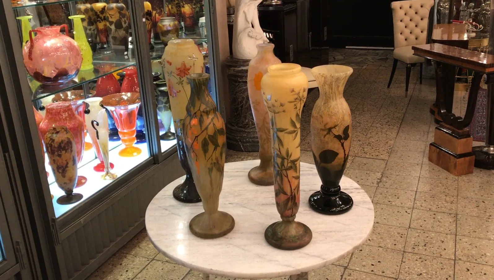 vista de coleção de antiguidades com vasos de vidro coloridos, incluindo o vidro assinado Daum Nancy.