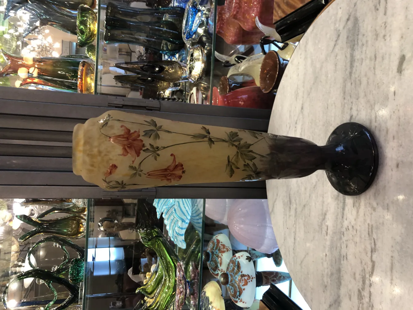 Vidro assinado antigo Daum Nancy com decoração floral em tons quentes, exibido em um ambiente vintage.