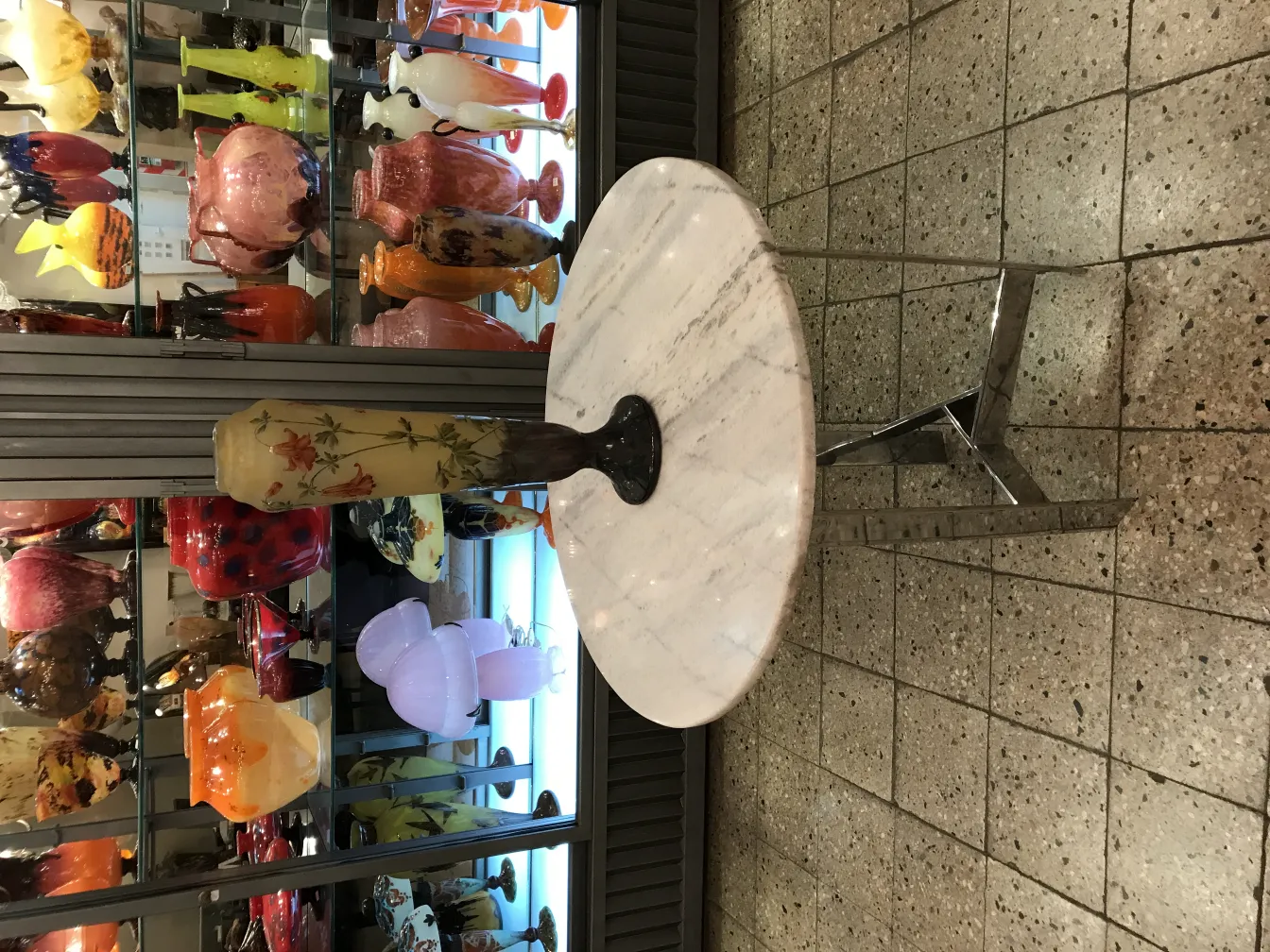 Vetro firmato Daum Nancy esposto tra vasi colorati.