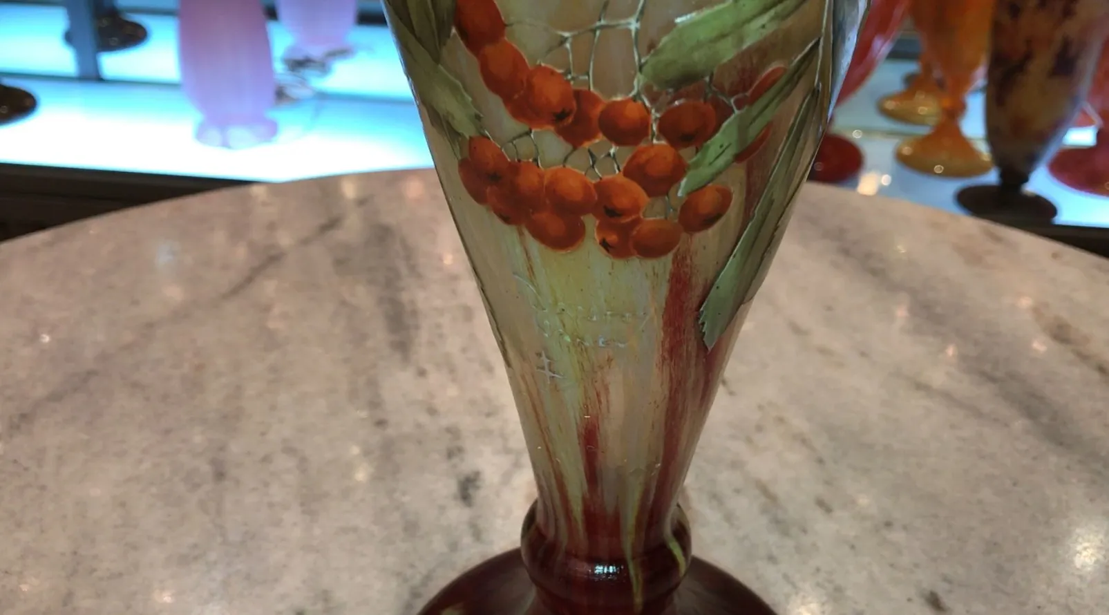 Antikes signiertes Glas Daum Nancy mit warmtoniger Blatt- und Beerendekoration, hellem Hintergrund.