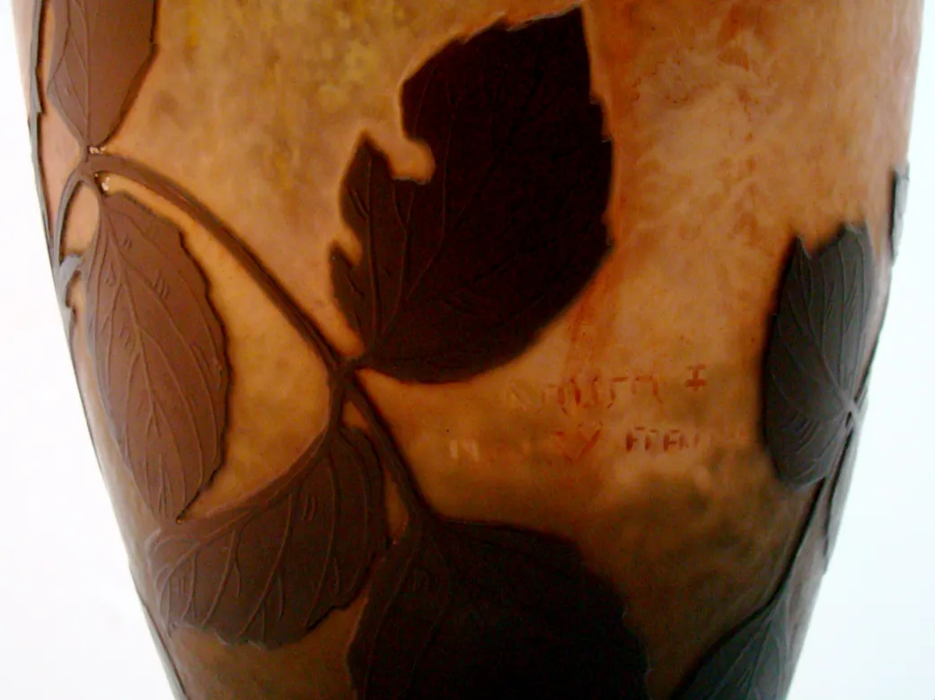 Vidrio firmado Daum Nancy con diseño de hojas en tonos cálidos.