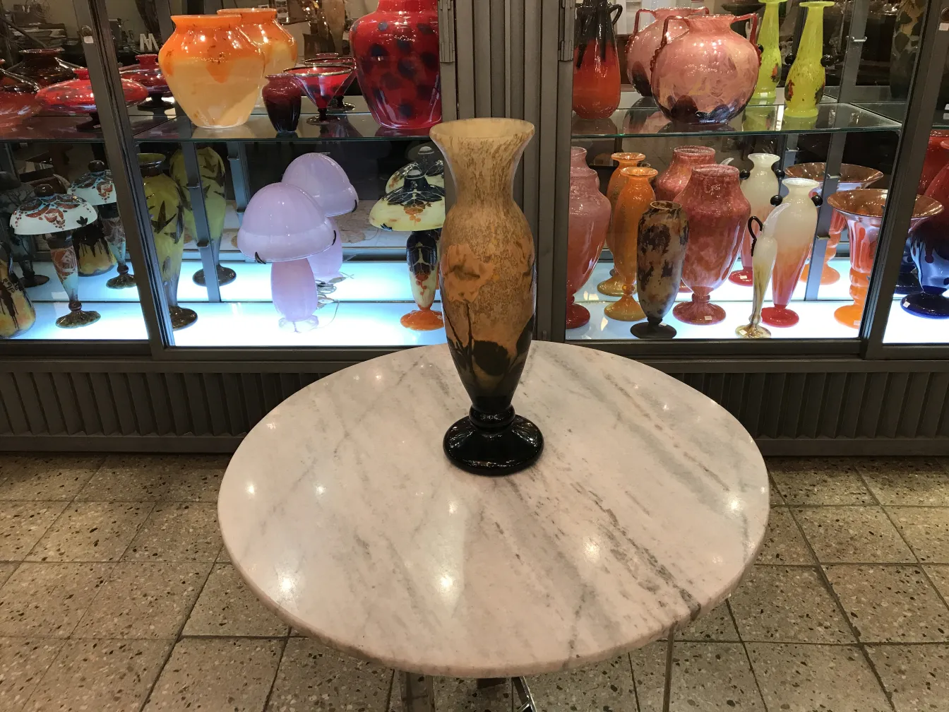 Vaso antico con firma Daum Nancy, circondato da altre antichità in vetro colorato.