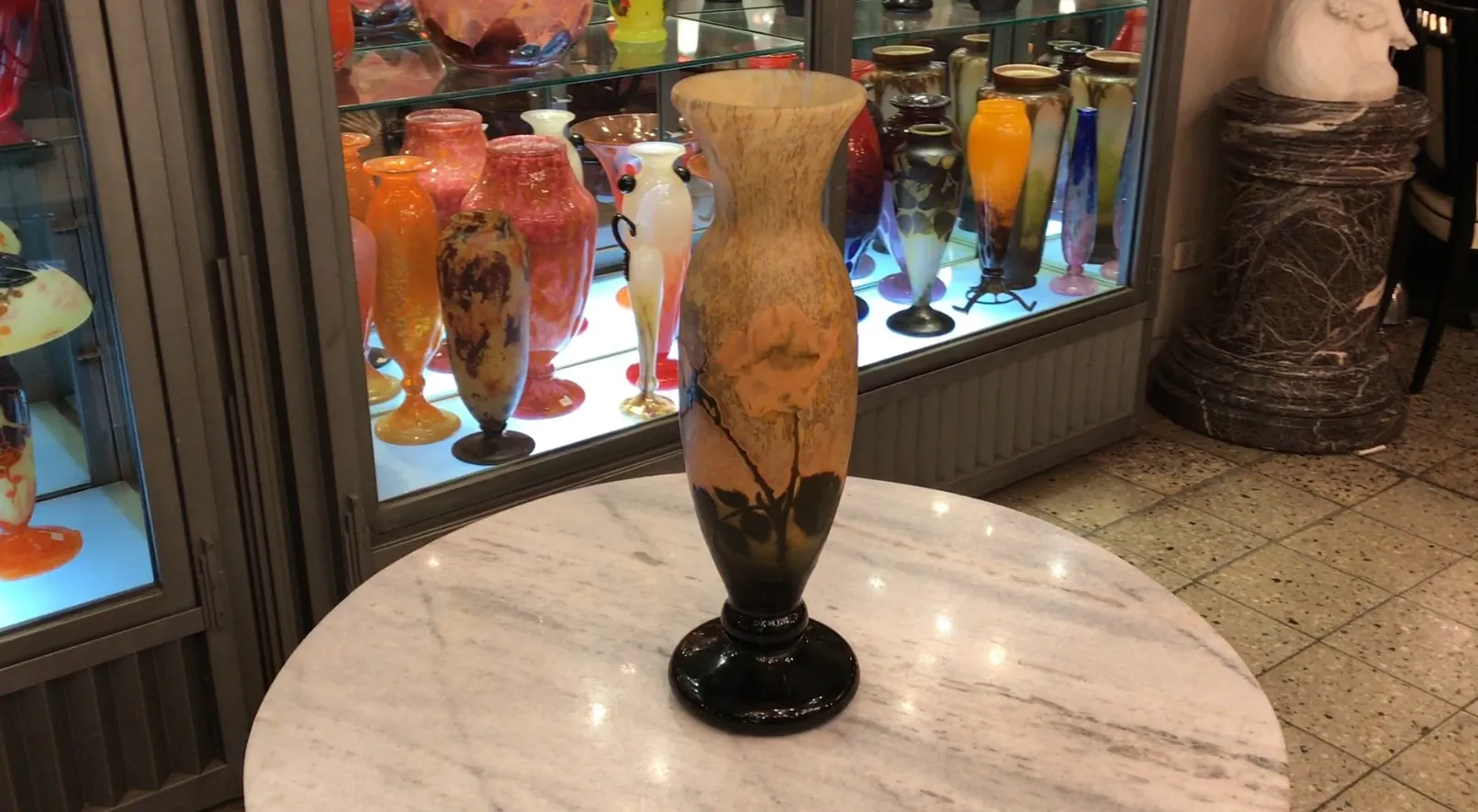 展出在展柜中的古董签名玻璃花瓶道姆南希，周围有色彩丰富的古董。